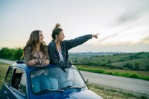 Tourists standing through car sunroof — Stock Photo