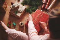 Frau wickelt Weihnachtsgeschenk mit Bindfaden ein — Stockfoto