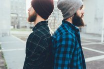 Male hipsters in knit hats back to back — Stock Photo