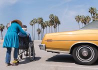 Жінка штовхає чоловіка в інвалідному візку — стокове фото
