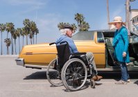 Seniorin plaudert mit Mann im Rollstuhl — Stockfoto