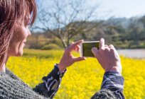 Mujer madura tomando fotos usando smartphone - foto de stock