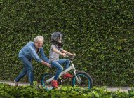 Großmutter schubst Enkel aufs Fahrrad — Stockfoto