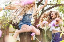 Girls in garden jumping in air — Stock Photo