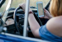 Woman using smartphone while driving — Stock Photo