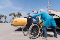 Женщина помогает мужу в инвалидном кресле — стоковое фото