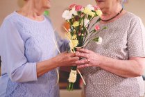 Femme donnant des fleurs à un ami — Photo de stock