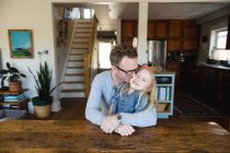 Чоловік сидить на кухні цілує дочку — стокове фото
