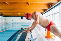 Uomo che si estende a bordo piscina — Foto stock