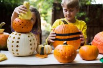 Girl and brother stacking carved pumpkins — Stock Photo