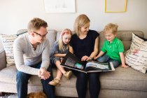 Батьки на дивані читають дітям — стокове фото