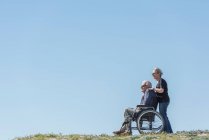 Donna spingendo marito in sedia a rotelle — Foto stock