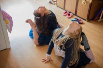Mädchen dehnen sich mit Zehen, die Köpfe berühren — Stockfoto