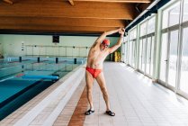 Uomo che si estende a bordo piscina — Foto stock