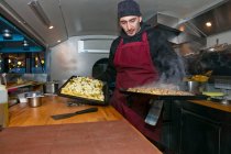Man preparing pizzas in food stall van at night — Stock Photo