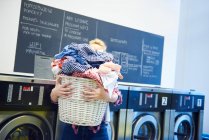Mujer llevando cesta de lavandería completa - foto de stock