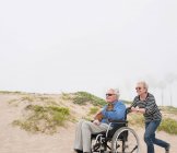 Старшая женщина толкает мужа в инвалидном кресле — стоковое фото