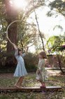 Sisters playing with hula hoop — Stock Photo