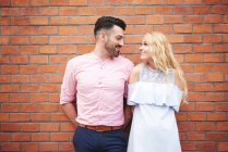 Couple in front of brick wall face to face — Stock Photo