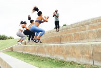 Mulheres jovens exercitando com formador — Fotografia de Stock