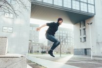 Хипстер прыгает в воздухе, практикуя паркур — стоковое фото