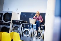 Frau sitzt auf Waschmaschine — Stockfoto