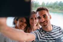 Three friends taking selfie with smartphone — Stock Photo