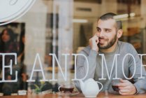 Молодой человек сидит в кафе — стоковое фото