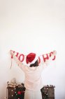 Вид сзади на молодую женщину, вешающую рождественские украшения на стену — стоковое фото