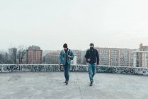 Hipsters masculins marchent sur la terrasse du toit de la ville — Photo de stock