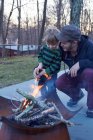 Boy and father tending fire in patio — Stock Photo