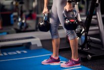 Young woman holding kettle bells — Stock Photo