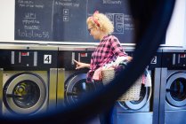 Frau drückt Waschmaschinenknöpfe — Stockfoto