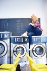 Laundrette owner sitting on top of washing machine — Stock Photo