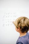 Boy doing sums on whiteboard — Stock Photo