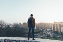 Hipster standing on city wall looking out — Stock Photo