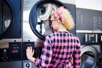 Woman pressing washing machine buttons — Stock Photo