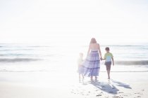 Madre e hijos en la playa - foto de stock
