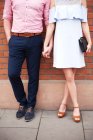 Couple holding hands in front of brick wall — Stock Photo