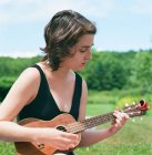 Jeune femme, en plein air, jouer ukulele — Photo de stock
