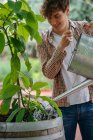 Junger Mann gießt Pflanze im Container — Stockfoto