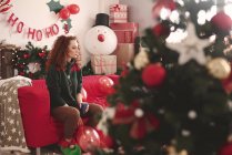 Сумна молода жінка сидить на дивані на Різдво — стокове фото