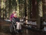 Старша жінка штовхає чоловіка в інвалідному кріслі — стокове фото