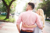 Couple walking arms around each other — Stock Photo