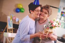 Woman giving flowers to friend — Stock Photo