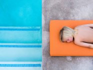 Garçon couché sur le bord de la piscine — Photo de stock