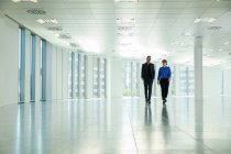 Businessman and woman walking through office — Stock Photo