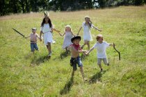 Niños con disfraces corriendo en el campo - foto de stock