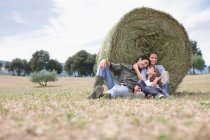 Pais e filha sentados no campo — Fotografia de Stock