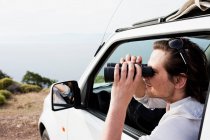 Homem no carro olhando através de binóculos — Fotografia de Stock
